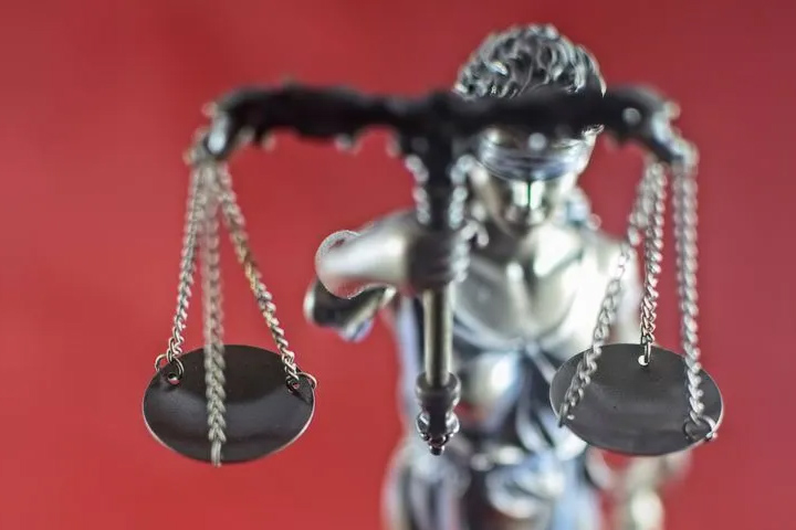 statue of scales of justice on a red background