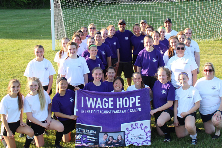 Pancreatic cancer patient Gregg Wittman surrounded by his soccer team, all in purple or white