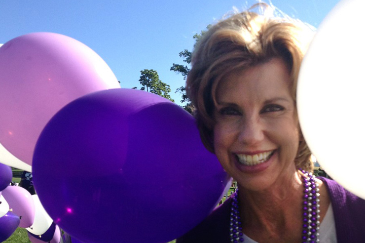 Long-term pancreatic cancer survivor Laurie MacCaskill surrounded by purple and white balloons