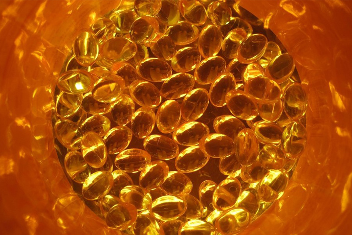 orange colored clear vitamin D pills in a circle against an orange background