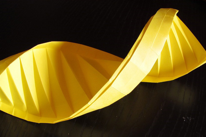 A yellow paper model of DNA helix against a dark background