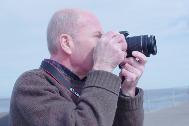 Long-term survivor of pancreatic cancer Steve Merlin on a boardwalk taking photos.