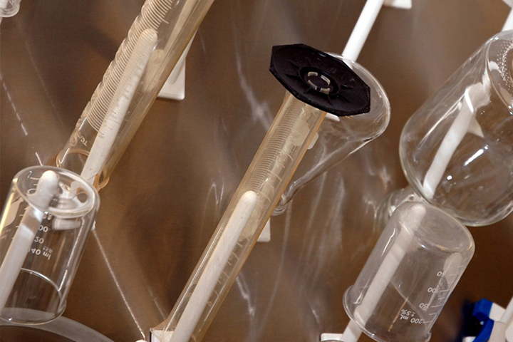 lab cylinders, beakers, glass bottles upside down on a drying rack