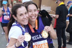 Two athletic women hugging after a marathon while displaying their medals