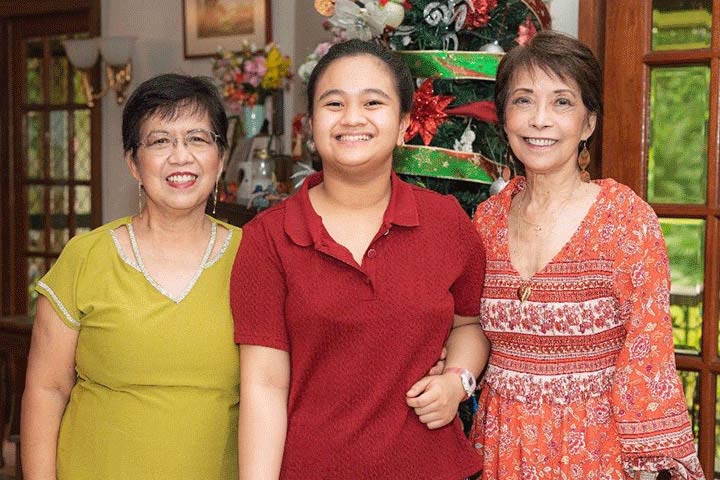 Three women, one in a green dress, the center one in a red top, and the right one in an orange and red printed dress.