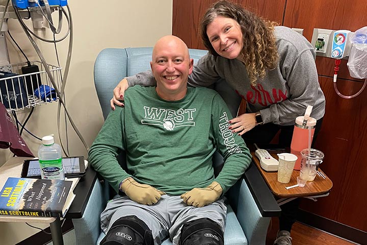 A bald man undergoing cancer treatment being cared for by his wife.