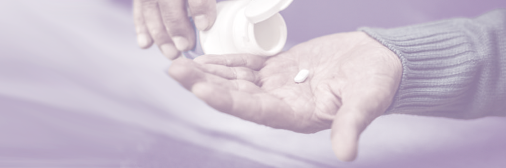 A hand with one pill and a bottle of pills.