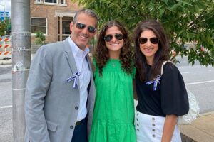 A group of three people dressed in nice clothes smiling together.