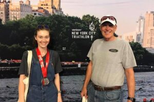 A woman with a race medal around her neck standing next to an older man.