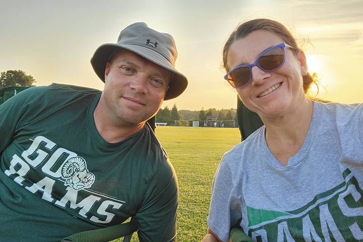 Man wearing a green shirt that says Go Rams, with a tan hat and a woman in sunglasses and a gray shirt that say Rams